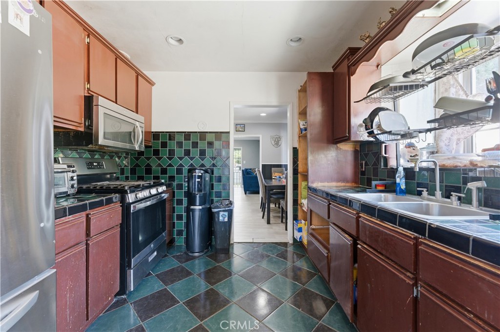 121 East 68th Way Long Beach, CA 90805 - Photo 6 of 17 a kitchen with stainless steel appliances granite countertop a stove a sink and a refrigerator