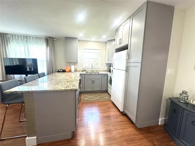 a kitchen with granite countertop kitchen island wooden floors and stainless steel appliances