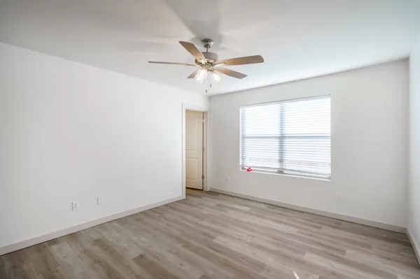 an empty room with a window and a ceiling fan