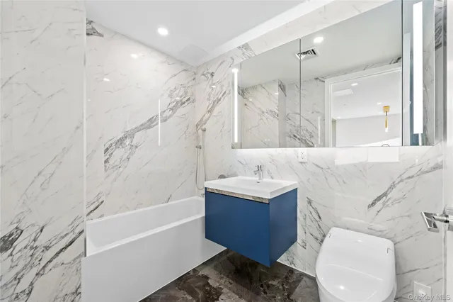 a bathroom with a bathtub shower sink vanity and toilet