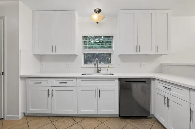 a kitchen with white cabinets and sink
