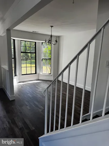 a view of an empty room with wooden floor and fan