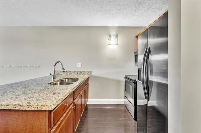 a kitchen with kitchen island granite countertop a sink and refrigerator