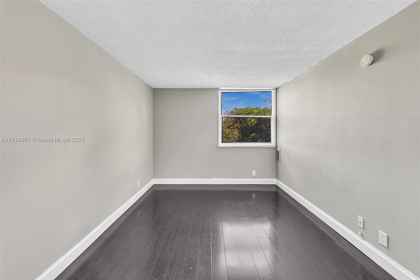 2701 Riverside Drive, Unit 303B Coral Springs, FL 33065 - Photo 6 of 19 an empty room with wooden floor and windows