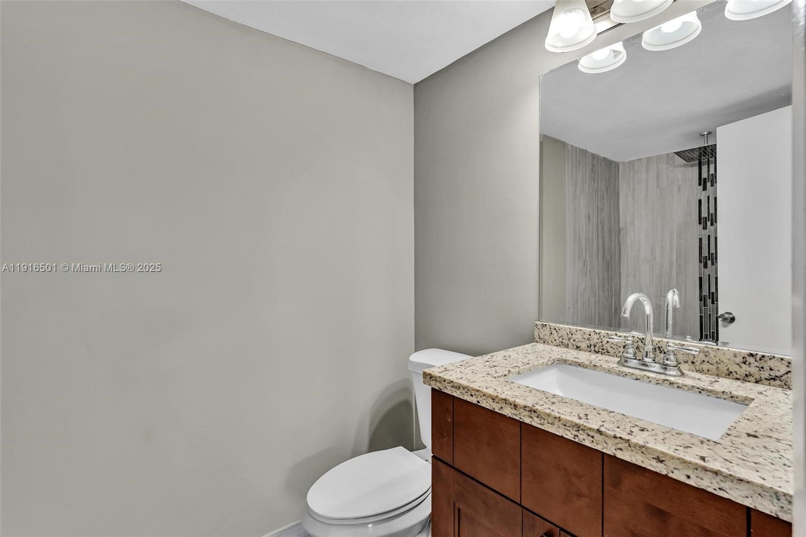 2701 Riverside Drive, Unit 303B Coral Springs, FL 33065 - Photo 10 of 19 a bathroom with a granite countertop toilet sink and mirror