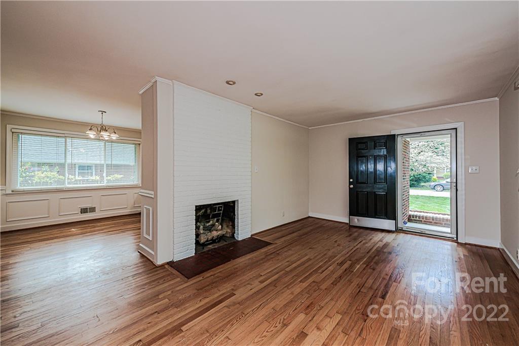 4301 Applegate Road Charlotte, NC 28209 - Photo 5 of 21 an empty room with wooden floor fireplace and windows