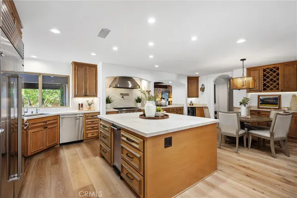 a kitchen with a stove a sink a kitchen island with chairs and wooden floor