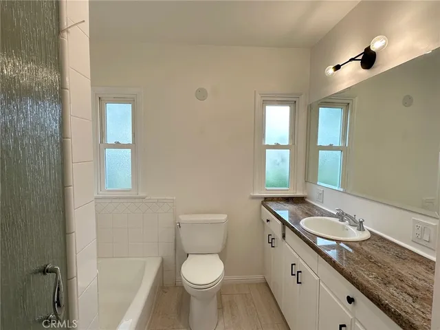 a bathroom with a granite countertop sink toilet and mirror
