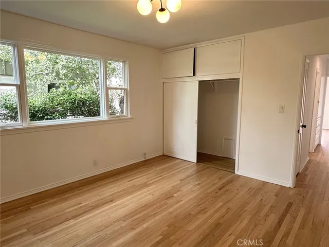 an empty room with wooden floor cabinet and windows