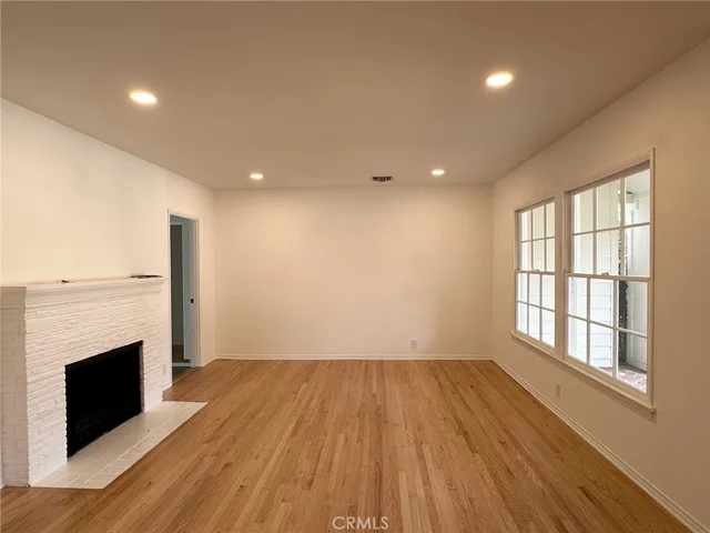 a view of empty room with wooden floor and fireplace