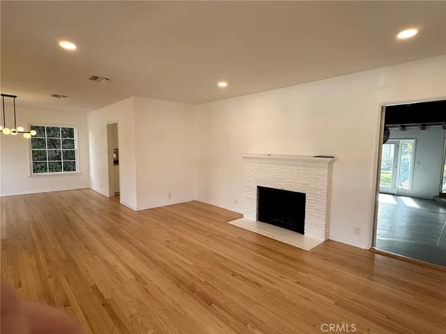 an empty room with wooden floor fireplace and windows