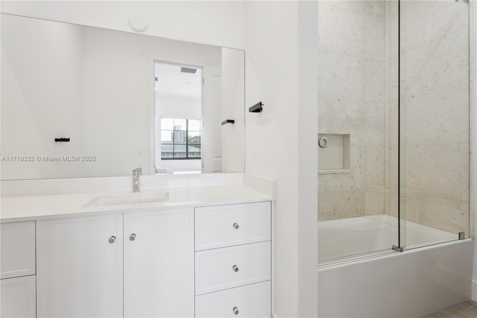 8391 Southwest 65th Avenue, Unit 8391 Miami, FL 33143 - Photo 16 of 24 a bathroom with a bathtub sink vanity and mirror