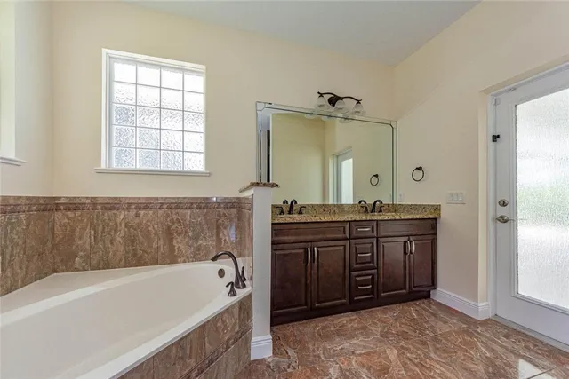 a spacious bathroom with a tub sink and mirror