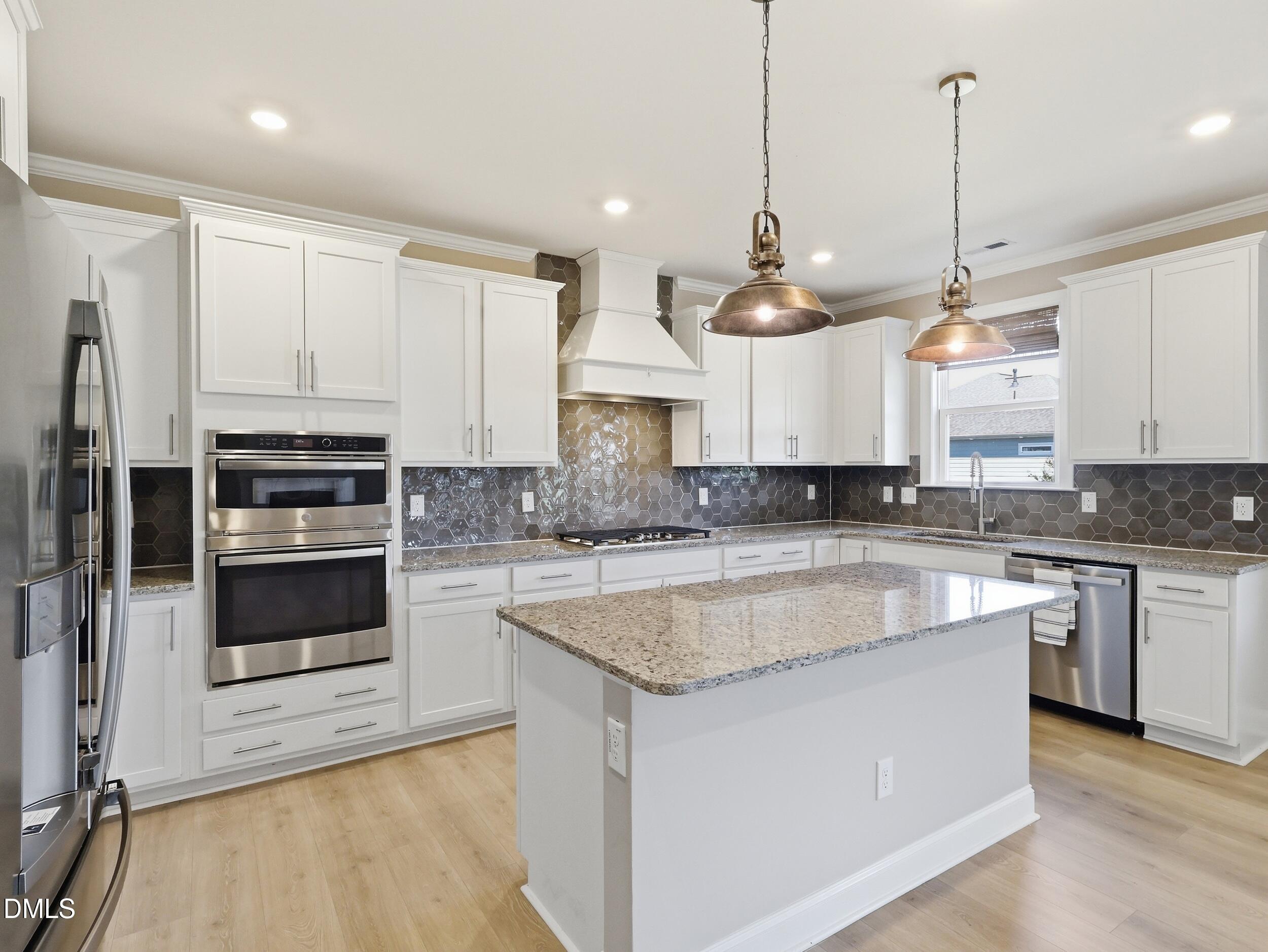 2709 Womble Ridge Drive New Hill, NC 27562 - Photo 17 of 60 a large kitchen with granite countertop a stove a sink a center island a refrigerator and a wooden floor