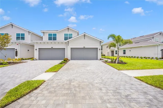 a view of a white house with a small yard and a large tree