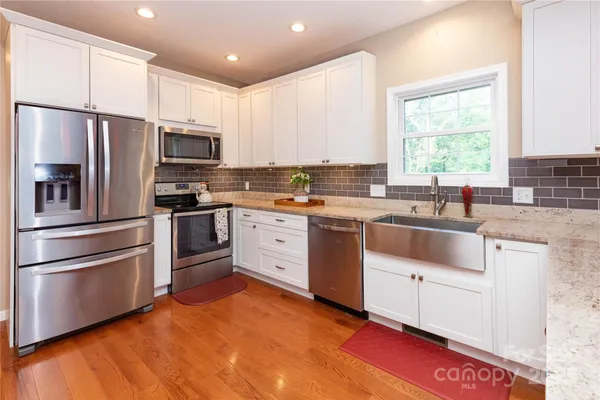 a kitchen with stainless steel appliances granite countertop a stove a sink dishwasher a refrigerator and a microwave