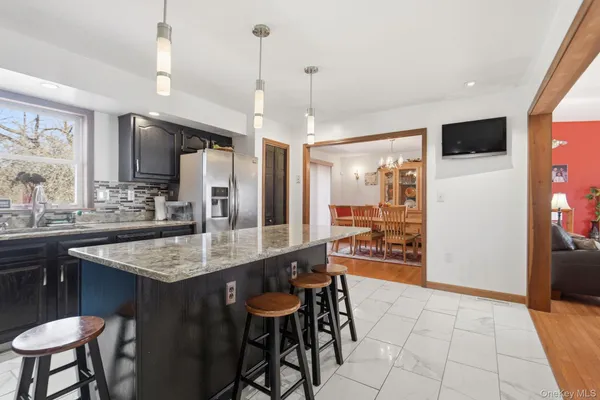 a kitchen with stainless steel appliances kitchen island granite countertop a table chairs and a refrigerator