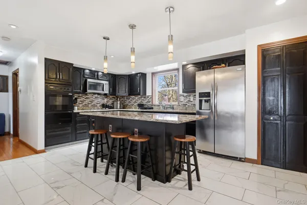 a kitchen with stainless steel appliances kitchen island granite countertop a refrigerator a stove a sink a dining table and chairs