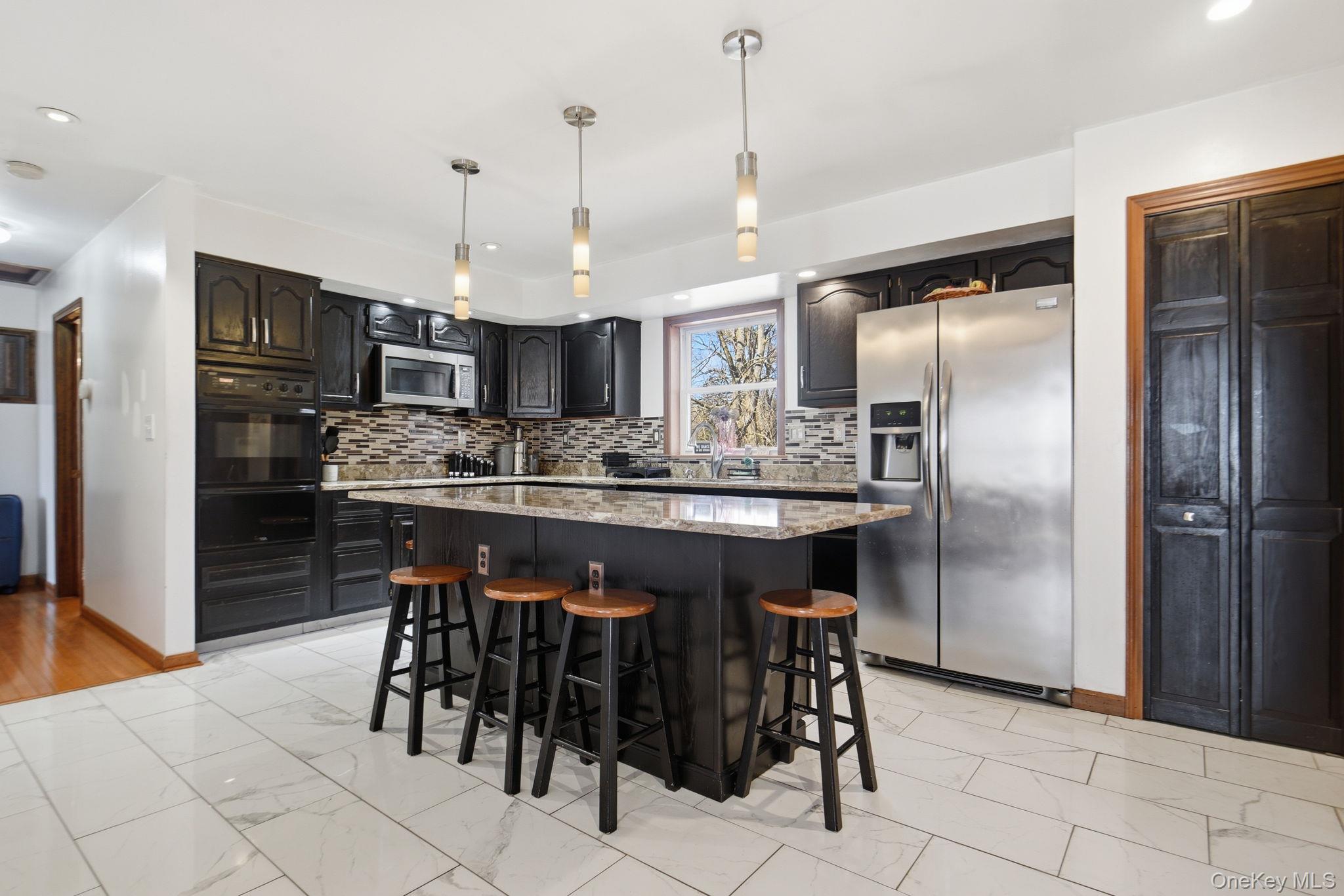 25 De Garmo Road Poughkeepsie, NY 12603 - Photo 19 of 50 a kitchen with stainless steel appliances kitchen island granite countertop a refrigerator a stove a sink a dining table and chairs