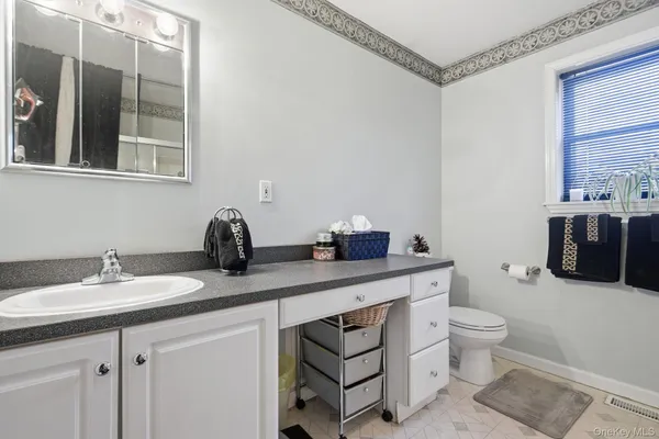 a spacious bathroom with a granite countertop sink a toilet and a mirror