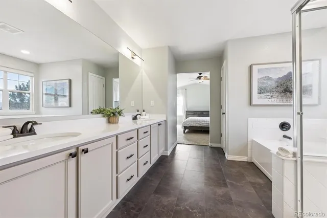 a spacious en suite bathroom with a double vanity sink a large mirror and a shower