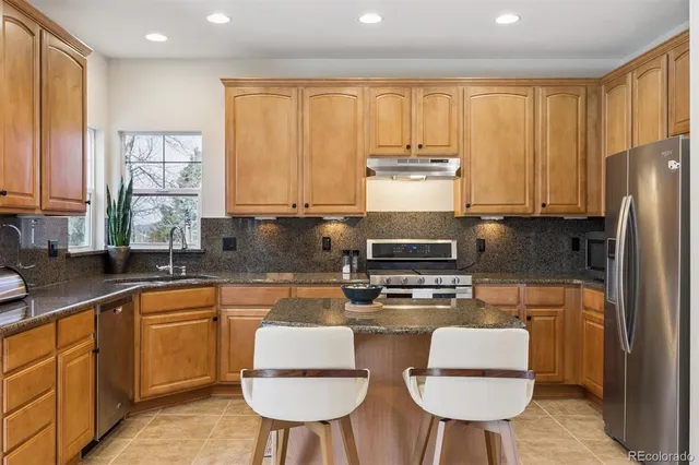 a kitchen with stainless steel appliances granite countertop a stove a sink dishwasher a refrigerator with white cabinets and wooden floor