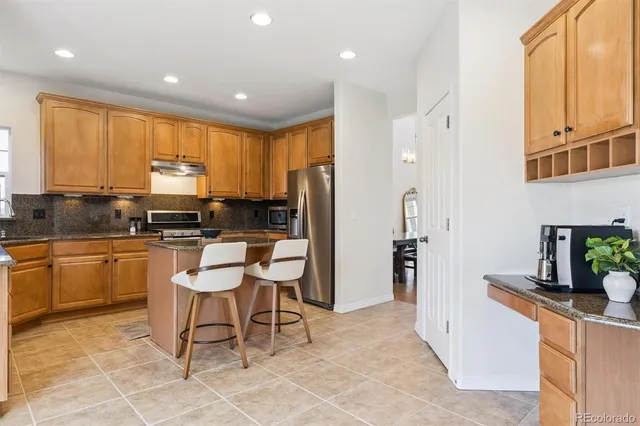 a kitchen with stainless steel appliances granite countertop a stove a sink a microwave a refrigerator and cabinets