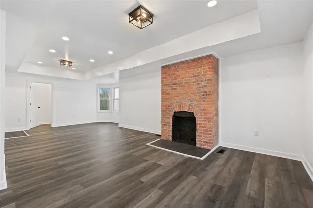 an empty room with wooden floor fireplace and windows