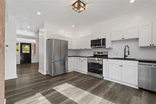 a kitchen with granite countertop a refrigerator stove top oven and sink