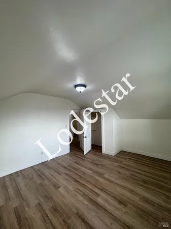 a view of an empty room with wooden floor and window