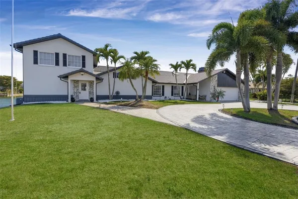 a front view of a house with a yard and palm trees