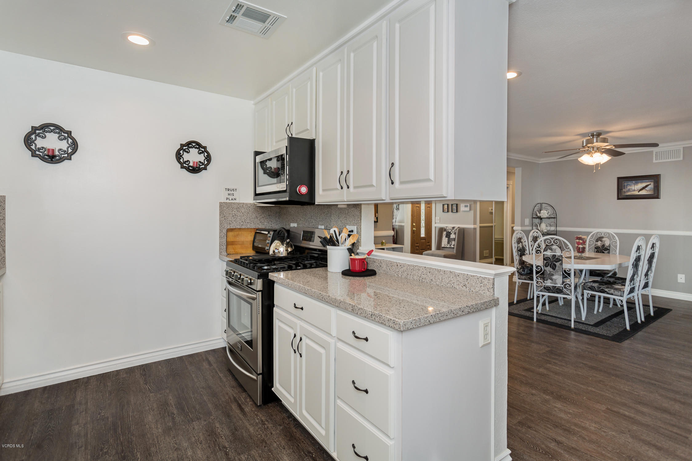 6295 Caroline Avenue Simi Valley, CA 93063 - Photo 14 of 27 a kitchen with stainless steel appliances granite countertop a stove top oven a sink a dining table and chairs with wooden floor