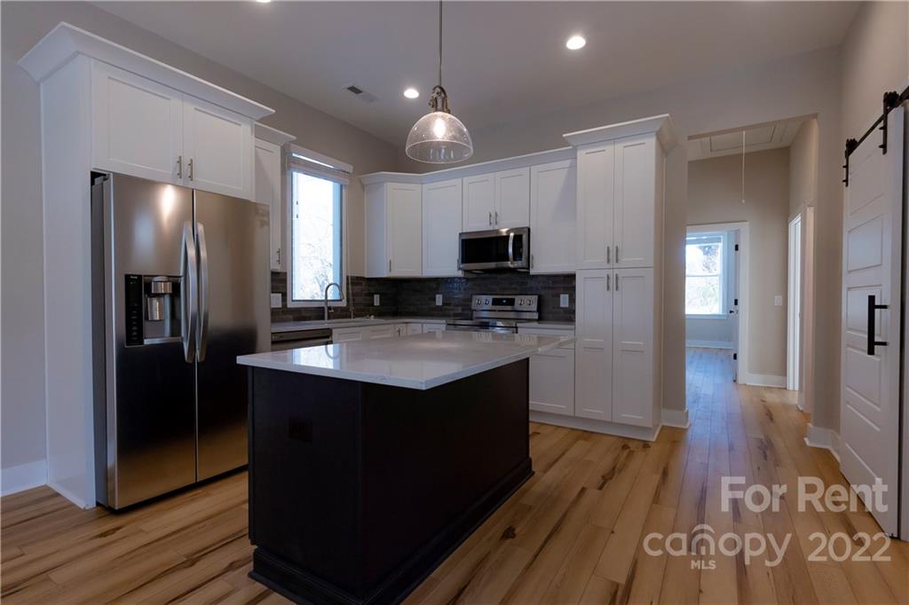 309 Houston Street, Unit B Davidson, NC 28036 - Photo 6 of 15 a kitchen with kitchen island granite countertop stainless steel appliances a sink cabinets and wooden floor