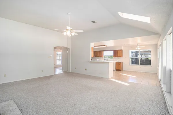 an empty room with chandelier fan and windows