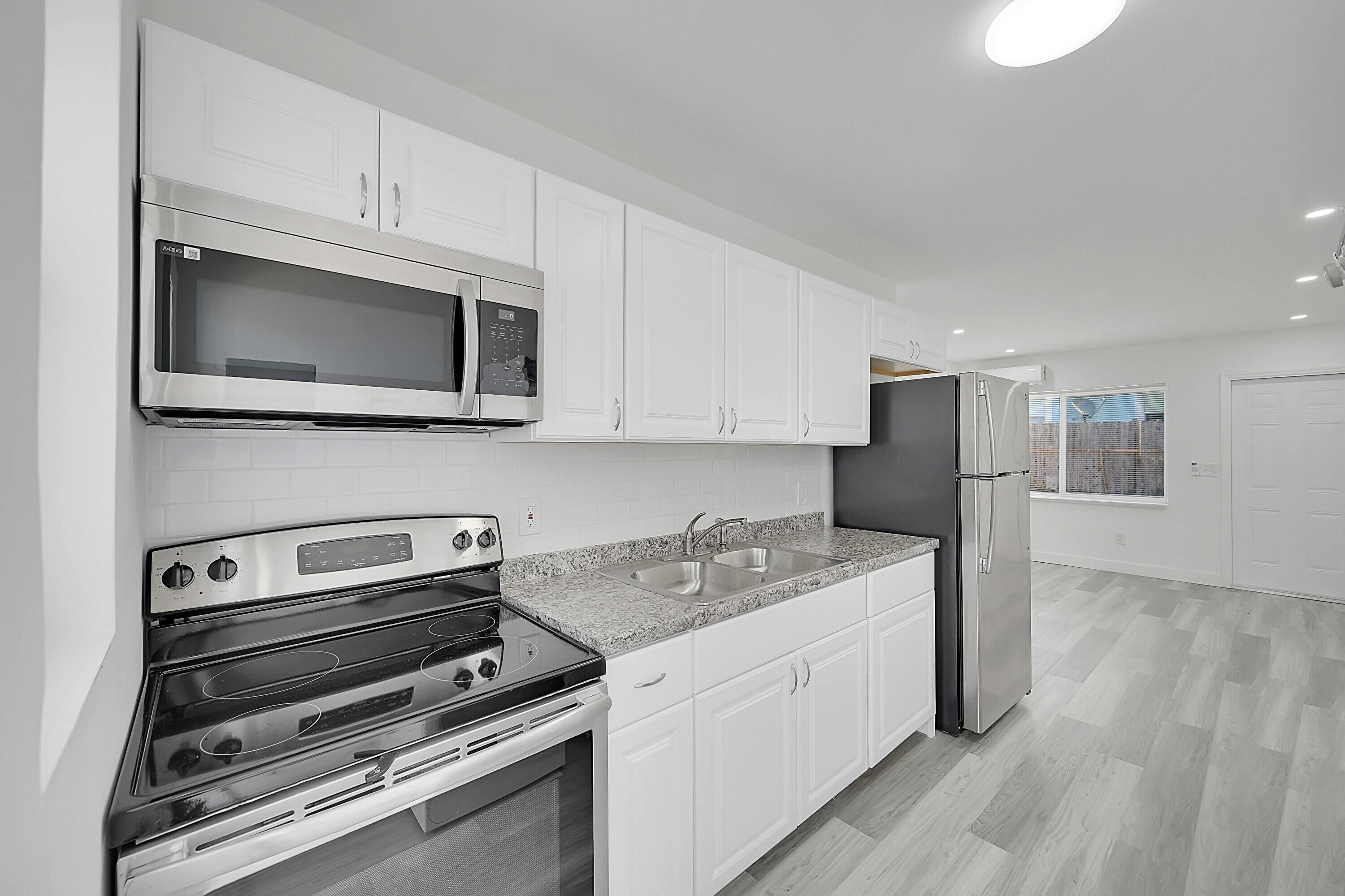 1157 West 36th Street, Unit 1 Riviera Beach, FL 33404 - Photo 3 of 12 a kitchen with stainless steel appliances granite countertop a stove microwave and refrigerator