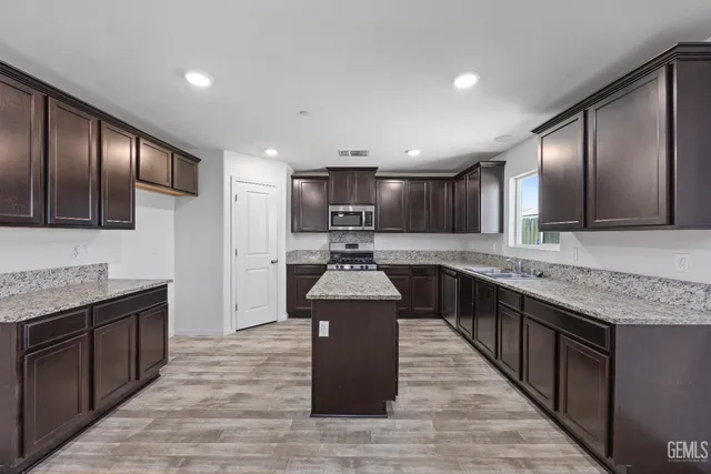 a kitchen with stainless steel appliances granite countertop wooden cabinets a sink and a stove