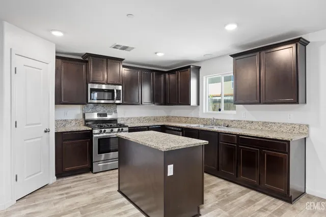 a kitchen with stainless steel appliances granite countertop wooden cabinets a stove top oven a sink and dishwasher
