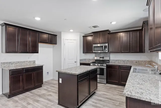 a kitchen with granite countertop wooden cabinets and stainless steel appliances