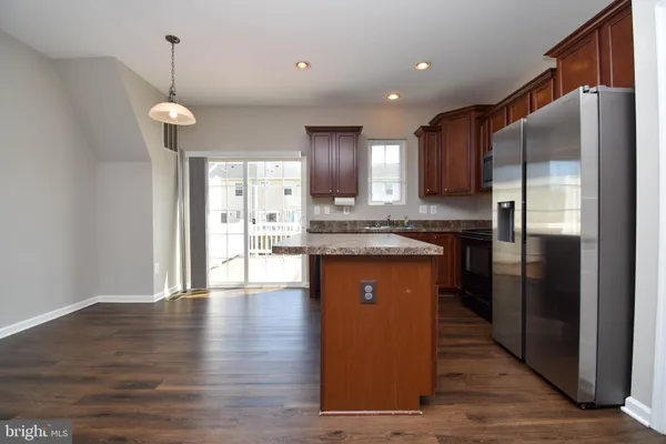 a kitchen with stainless steel appliances granite countertop a refrigerator a sink dishwasher and a oven with wooden floor