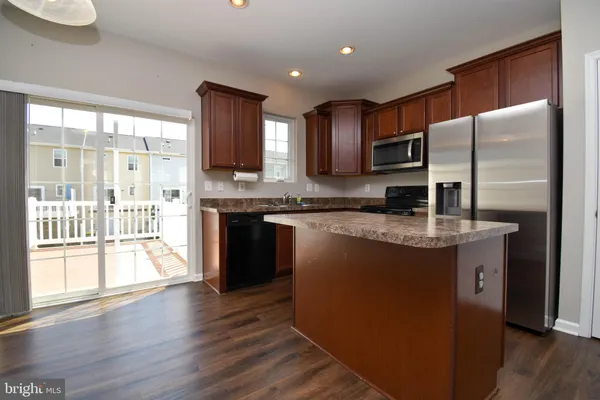 a kitchen with stainless steel appliances granite countertop a refrigerator a sink dishwasher a stove with wooden cabinets and floor