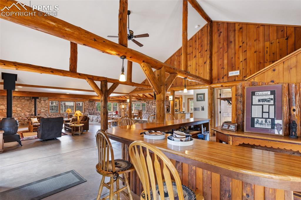 1100 Rampart Range Road Woodland Park, CO 80863 - Photo 8 of 50 The sprawling great room features a vaulted ceiling with log beams, open floor plan with two wood-burning stoves and the original bar