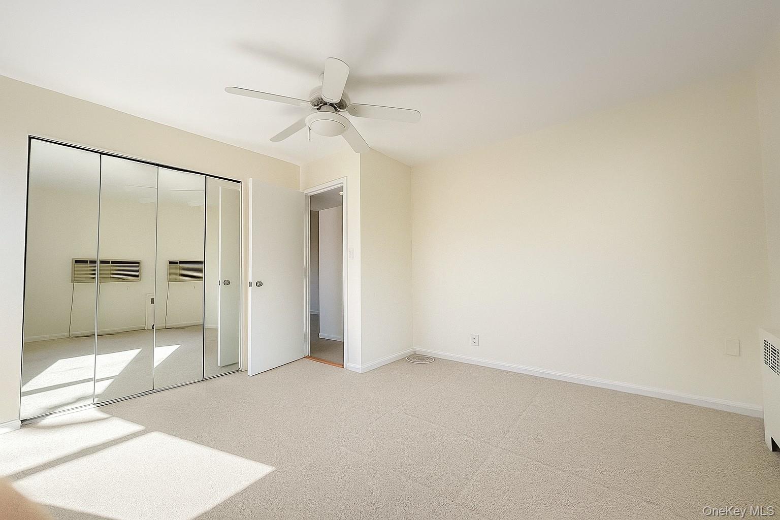 7 Terrace, Unit 3H Great Neck, NY 11021 - Photo 11 of 37 an empty room with a ceiling fan and glass door