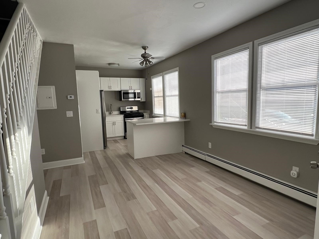 238 Appleton Street, Unit 1 Lowell, MA 01852 - Photo 3 of 5 a view of a kitchen with a refrigerator wooden floor and a window