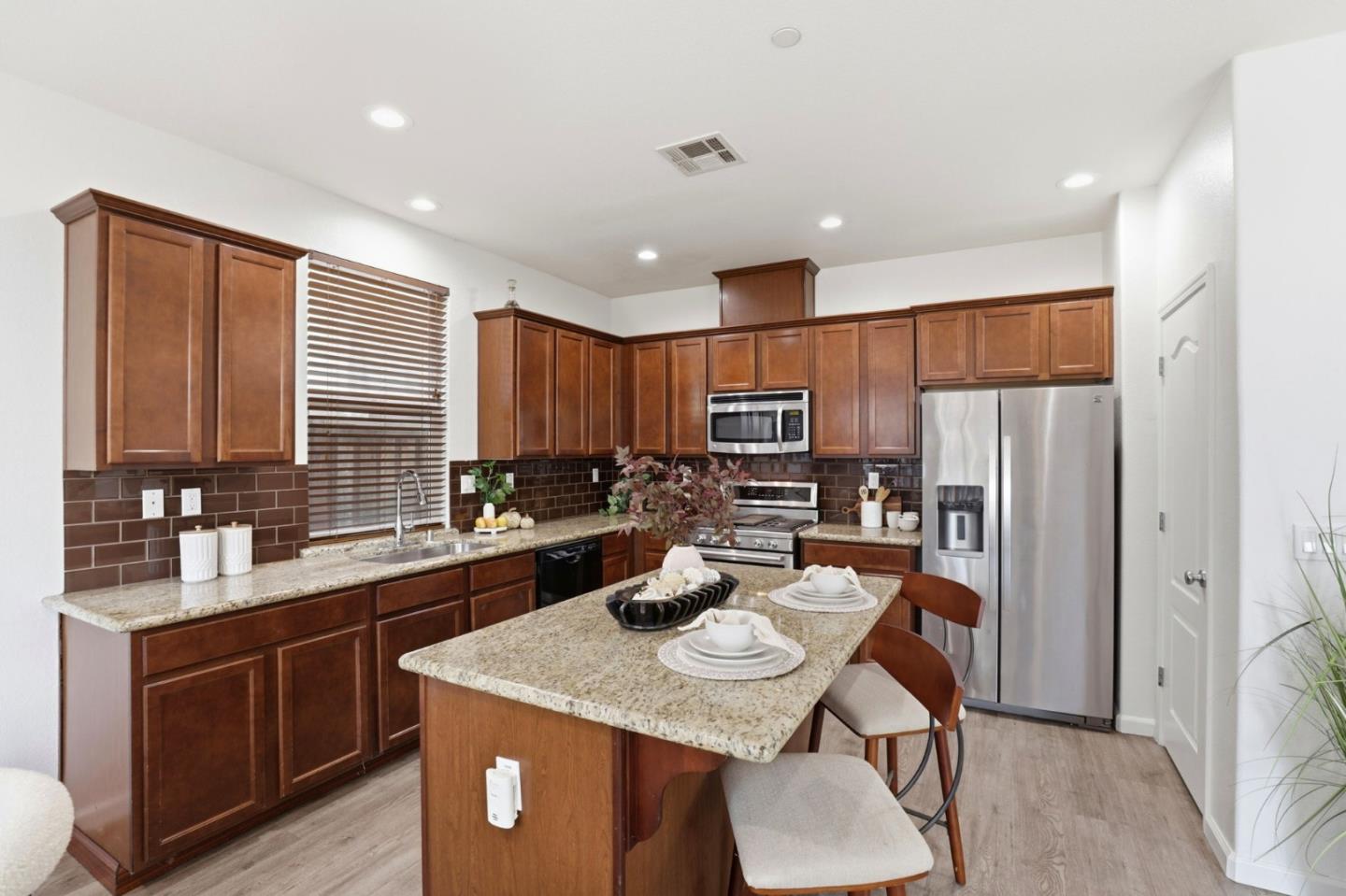 170 Sturla Way Gilroy, CA 95020 - Photo 13 of 64 a kitchen with stainless steel appliances granite countertop a kitchen island a stove a sink a refrigerator and cabinets