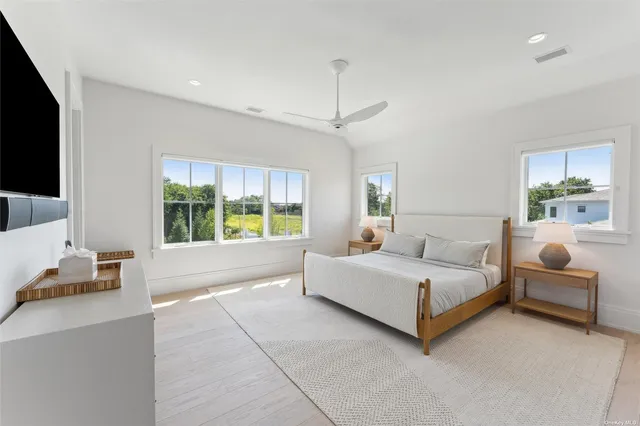 a living room with a bed furniture flat screen tv and a large window