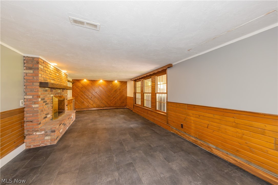 7969 Dines Road Novelty, OH 44072 - Photo 33 of 48 Spacious family room featuring a prominent brick fireplace with a wood mantel, wood-finish flooring, and natural wood paneling on walls