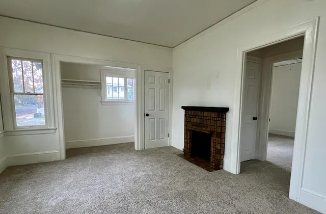 an empty room with windows and fireplace