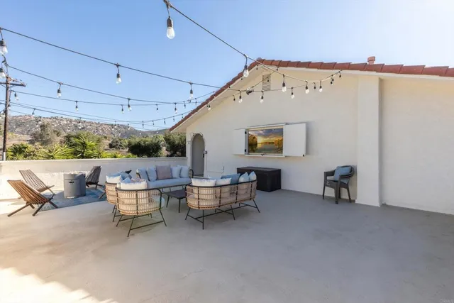 a view of a white house with a large windows and a yard with plants and large trees