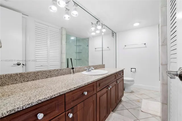 a bathroom with a granite countertop double vanity sink and mirror