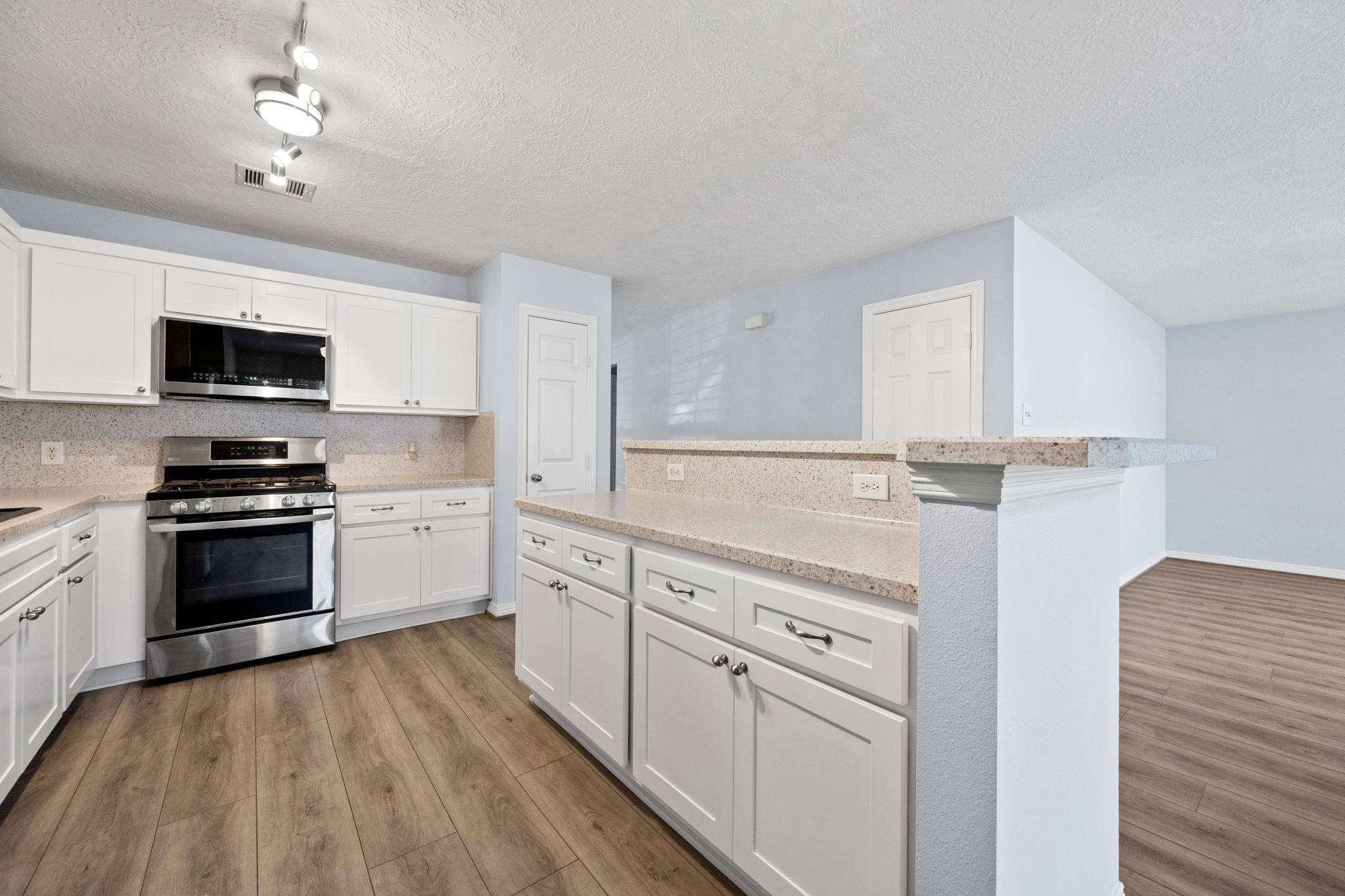 21893 Pinewilde Court Porter, TX 77365 - Photo 19 of 25 a kitchen with stainless steel appliances white cabinets a sink a stove a microwave and wooden floors